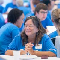 Woman with hands together on table, looking off camera